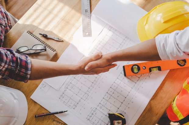 top view construction worker team contractor hand shake after finishing up business meeting to greeting start up project contract in construction site building, teamwork, partnership, industry concept