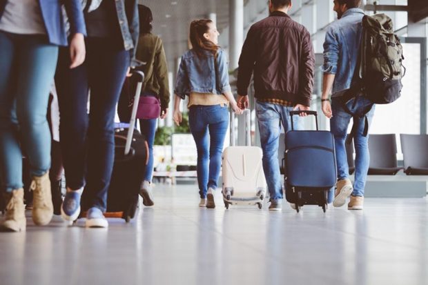 Passengers walking in the airport corridor with luggage. Travelling people at airport terminal.